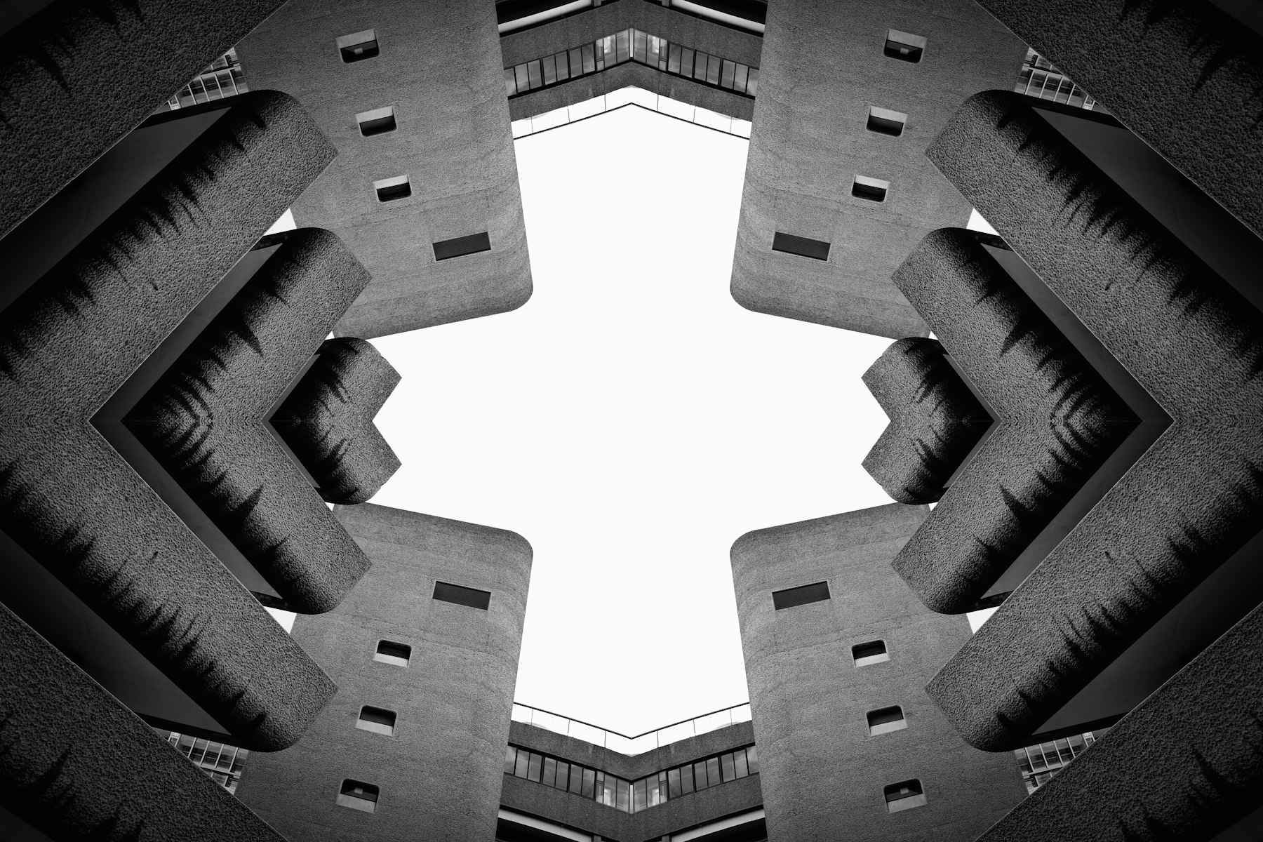 Symmetrical view looking up through a brutalist concrete courtyard