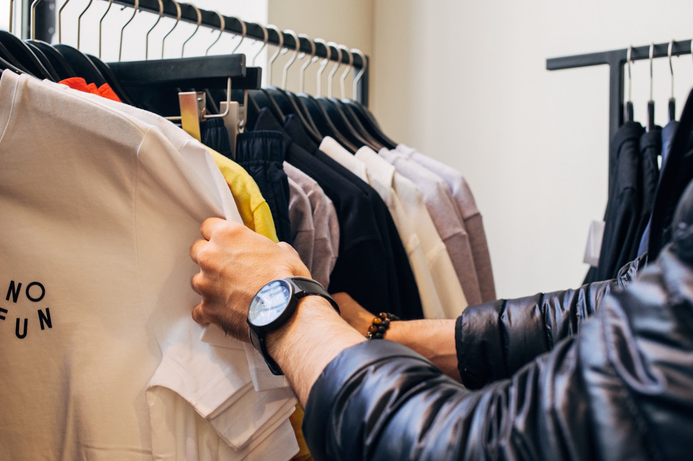 Hand pulling a folded shirt from a clothing rack