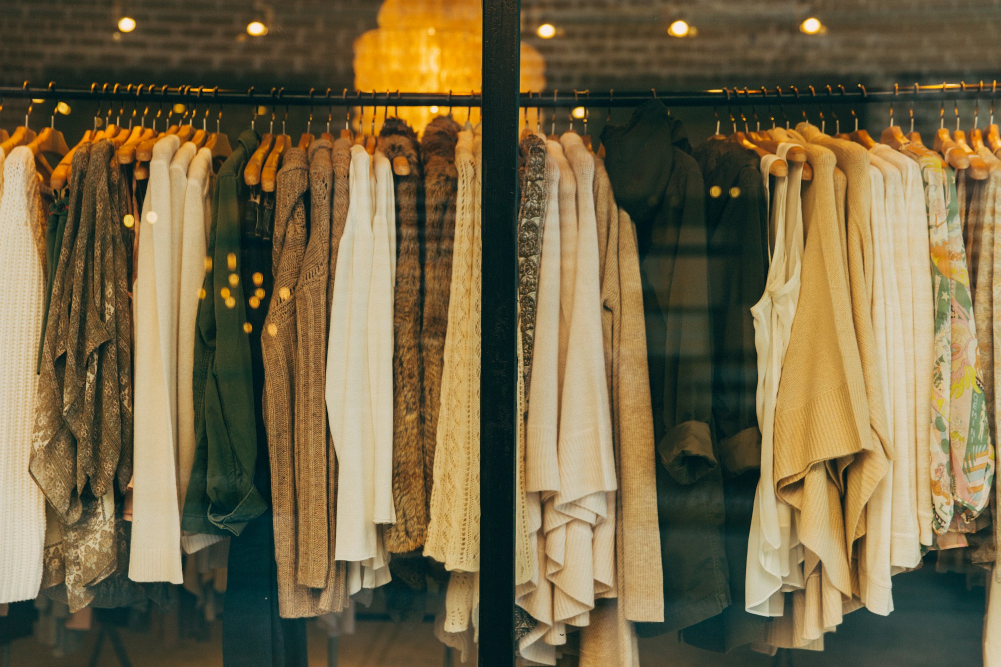 Rack of folded knitwear and outerwear in warm neutral tones